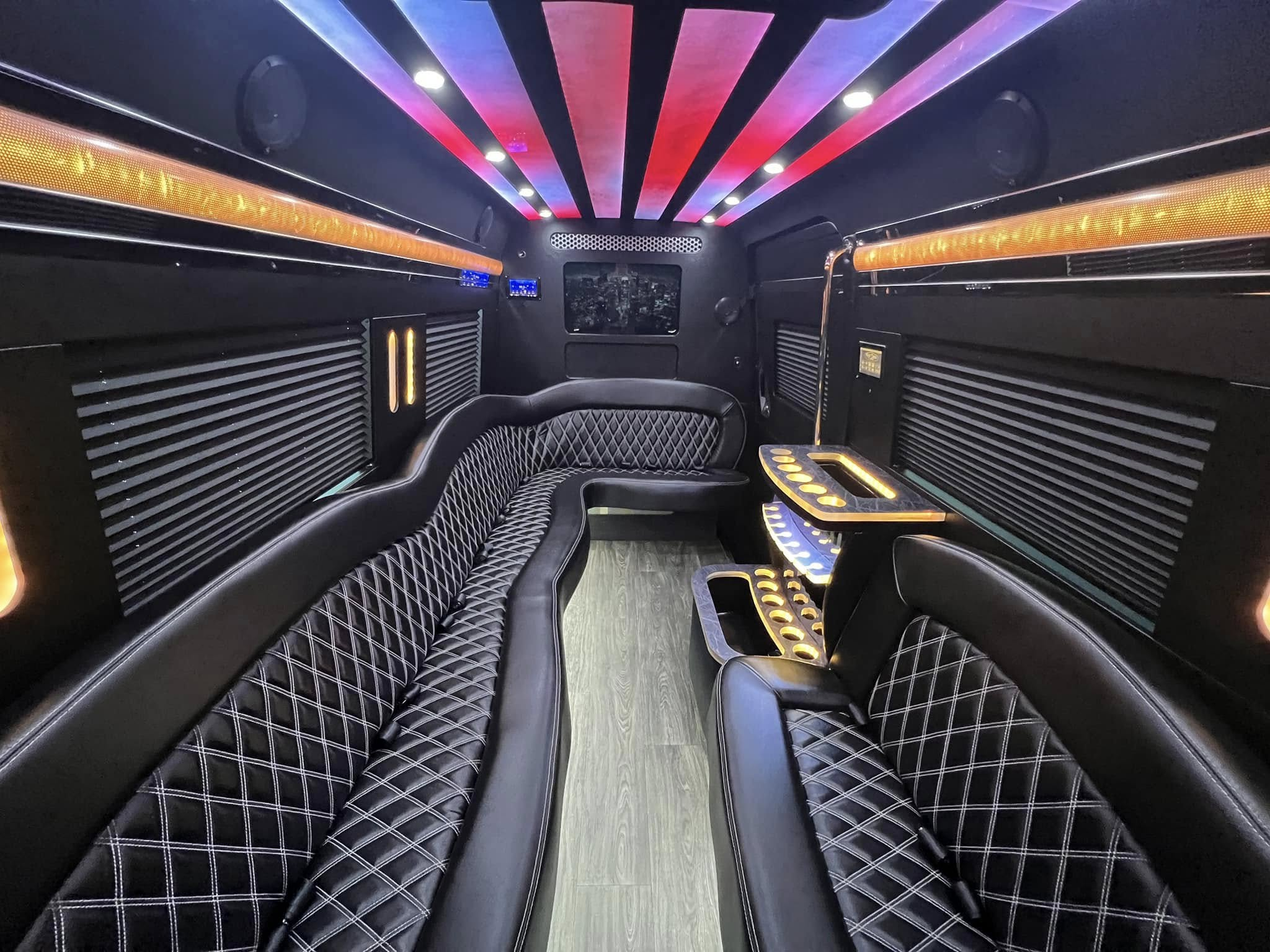 Limousine interior with diamond-stitched black seating, illuminated cupholders, and colorful ceiling panels