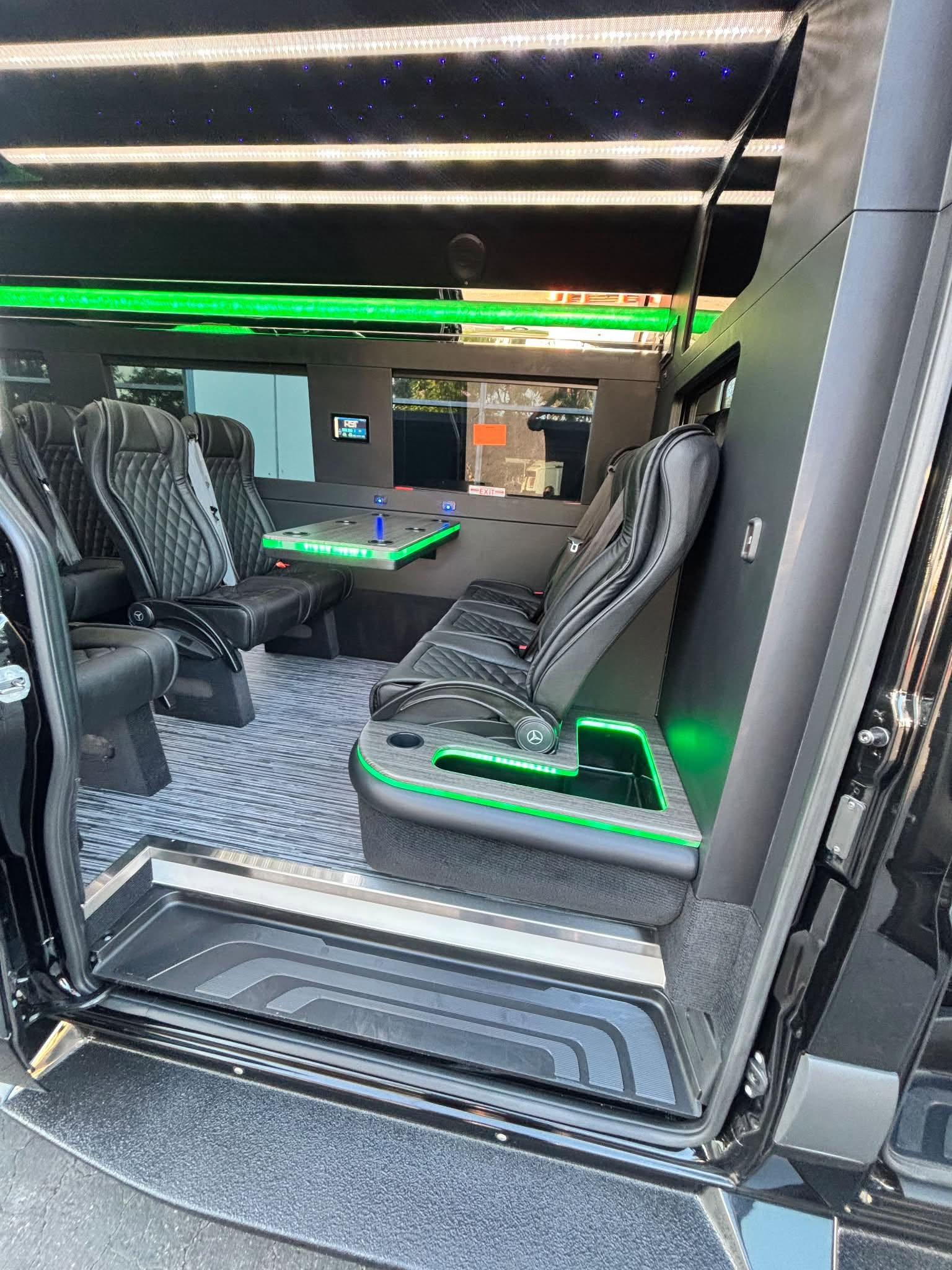 Passenger interior with black quilted seats, a table, and green accent lighting